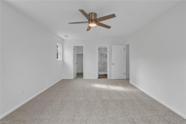 unfurnished bedroom featuring ceiling fan, light colored carpet, a walk in closet, and connected bathroom