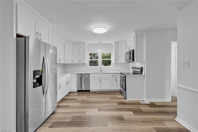 kitchen featuring white cabinetry, sink, light wood-type flooring, and appliances with stainless steel finishes