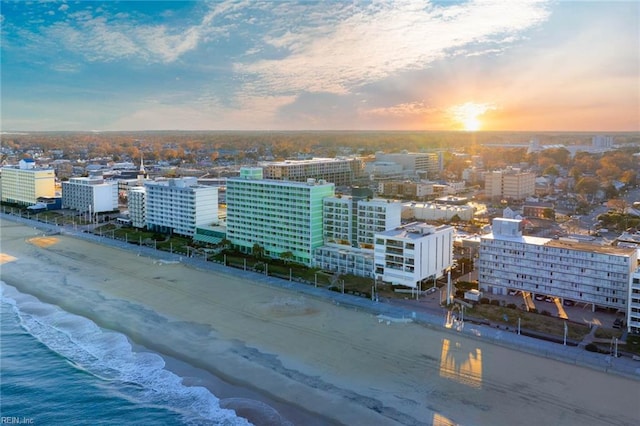 aerial view at dusk featuring a view of the beach and a water view