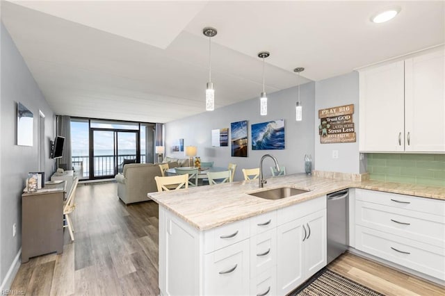 kitchen with kitchen peninsula, white cabinetry, dishwasher, and sink