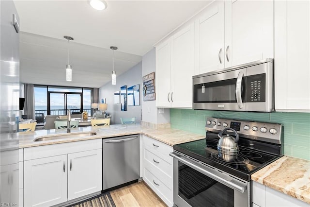 kitchen featuring decorative backsplash, appliances with stainless steel finishes, light wood-type flooring, sink, and white cabinets