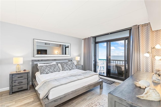 bedroom with access to exterior, a water view, and light wood-type flooring