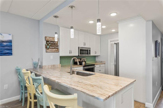 kitchen with kitchen peninsula, a breakfast bar, stainless steel appliances, and hanging light fixtures