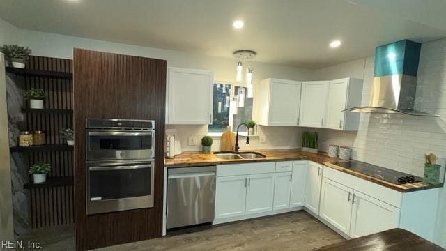 kitchen featuring white cabinets, wall chimney exhaust hood, sink, and stainless steel appliances