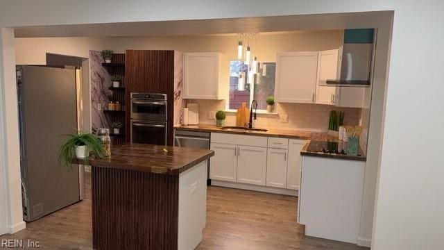 kitchen featuring appliances with stainless steel finishes, light wood-type flooring, a kitchen island, and sink