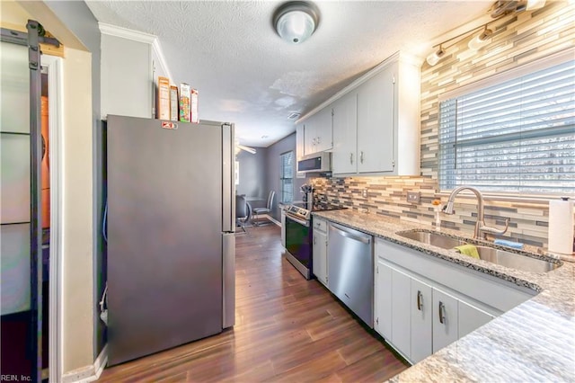 kitchen with light stone countertops, sink, backsplash, a textured ceiling, and appliances with stainless steel finishes