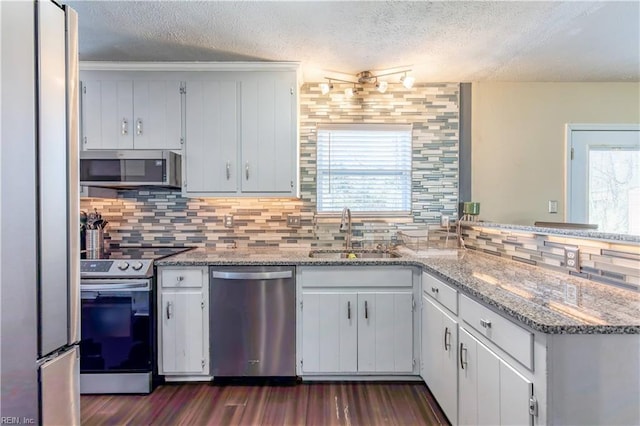 kitchen with light stone counters, sink, white cabinets, and appliances with stainless steel finishes