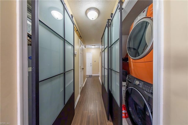 laundry area featuring a textured ceiling, dark hardwood / wood-style floors, and stacked washer and dryer