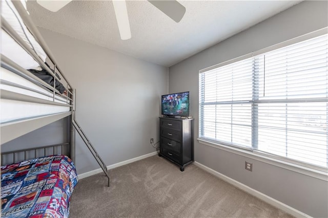 carpeted bedroom with multiple windows, a textured ceiling, and ceiling fan