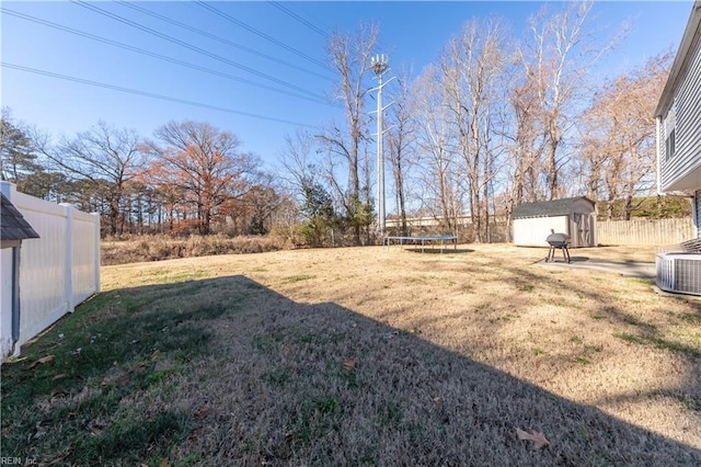 view of yard featuring a storage shed, a trampoline, and central AC