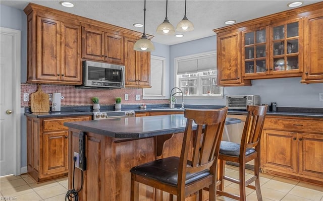 kitchen with a center island, light tile patterned floors, decorative light fixtures, a kitchen bar, and stainless steel appliances