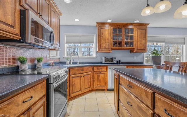 kitchen featuring decorative light fixtures, stainless steel appliances, a wealth of natural light, and sink