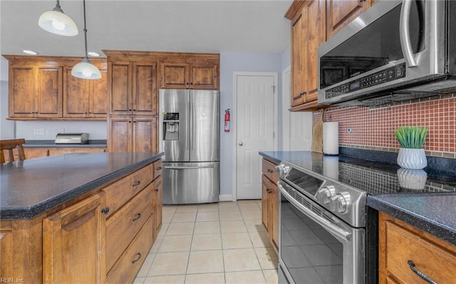 kitchen featuring backsplash, hanging light fixtures, light tile patterned floors, and stainless steel appliances