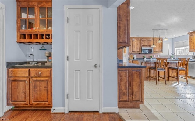 kitchen featuring a textured ceiling, stainless steel appliances, sink, decorative light fixtures, and light hardwood / wood-style flooring