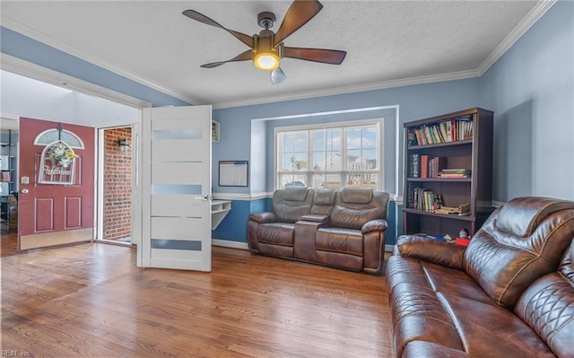 living room featuring ceiling fan, ornamental molding, a textured ceiling, and hardwood / wood-style flooring