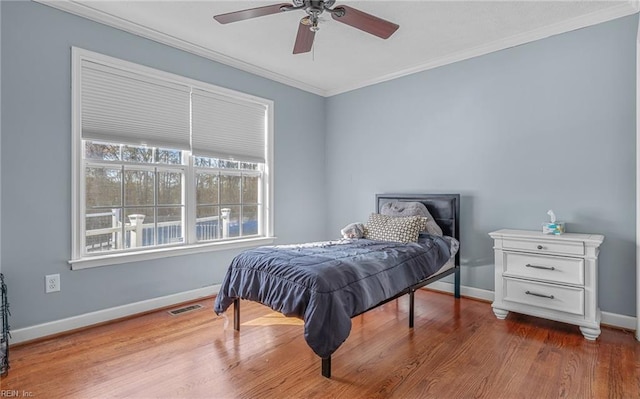 bedroom with ceiling fan, ornamental molding, and hardwood / wood-style flooring