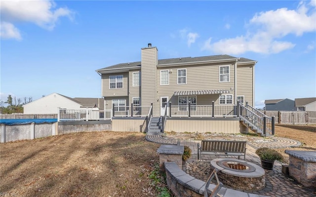 rear view of property featuring a swimming pool side deck and an outdoor fire pit