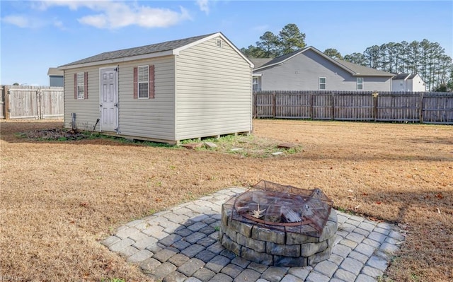 rear view of property featuring a yard, a patio, an outdoor fire pit, and an outdoor structure