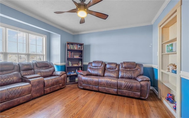 living room featuring ceiling fan, light hardwood / wood-style floors, ornamental molding, and built in shelves