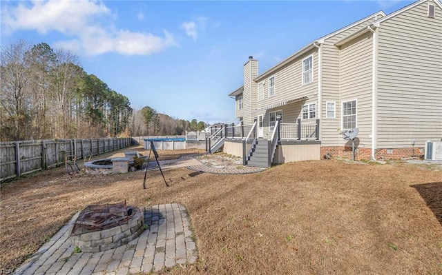 view of yard featuring an outdoor fire pit, a pool side deck, and central air condition unit