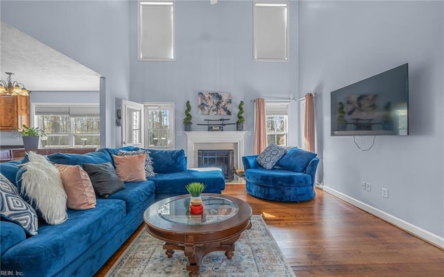 living room with a high ceiling, a chandelier, a textured ceiling, and hardwood / wood-style flooring