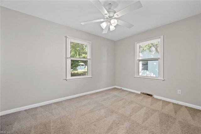 carpeted empty room with a wealth of natural light and ceiling fan