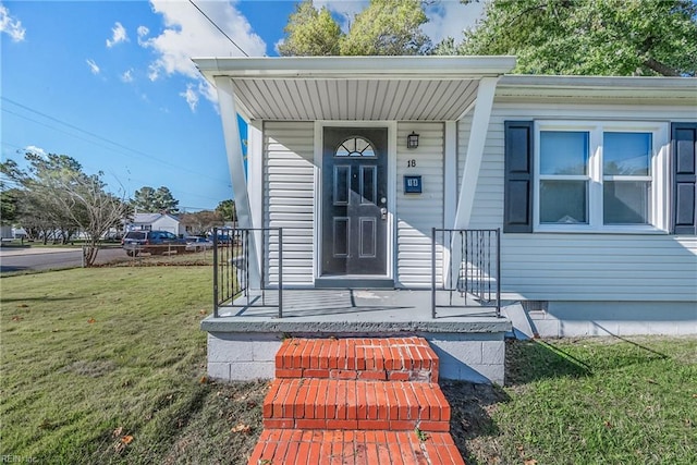 view of exterior entry featuring a yard and covered porch