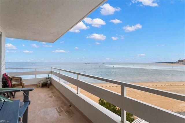 balcony featuring a view of the beach and a water view