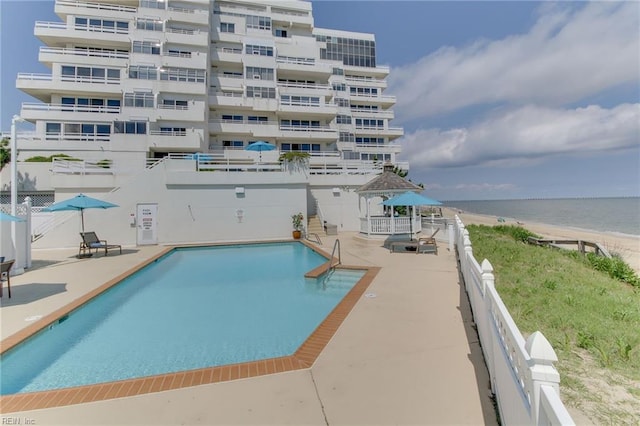 view of pool with a view of the beach, a patio, and a water view