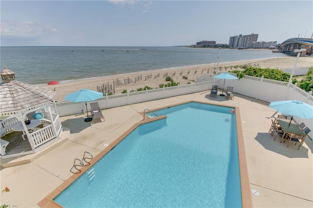 view of swimming pool featuring a gazebo, a water view, a patio, and a beach view