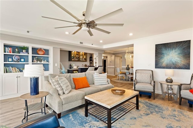 living room with ceiling fan with notable chandelier, hardwood / wood-style flooring, and ornamental molding