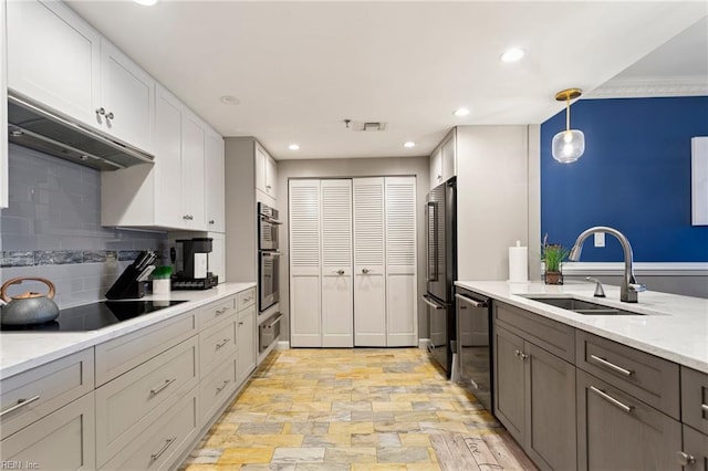 kitchen with appliances with stainless steel finishes, backsplash, sink, white cabinets, and hanging light fixtures