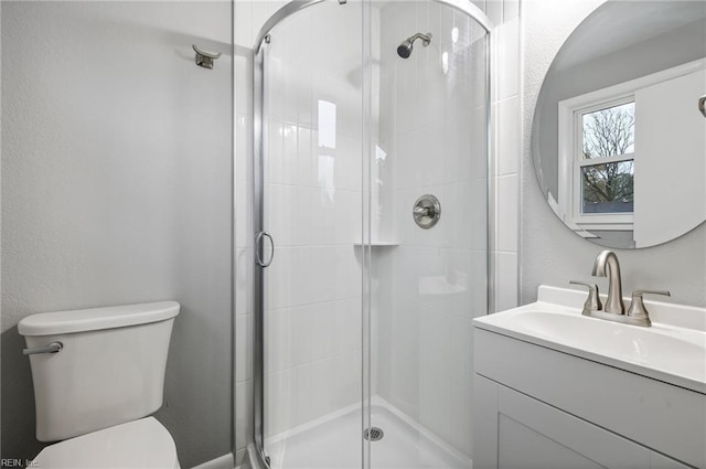 bathroom featuring a shower with door, vanity, and toilet