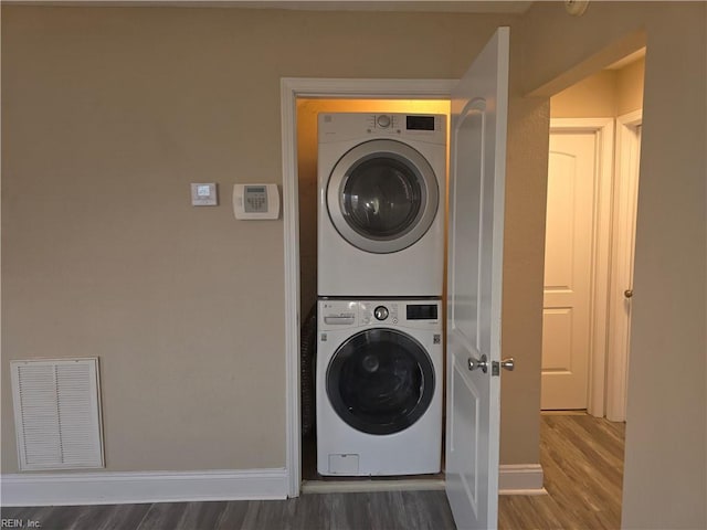 washroom with hardwood / wood-style floors and stacked washer and clothes dryer