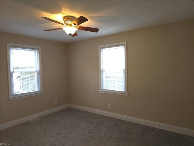 unfurnished room with ceiling fan and dark carpet