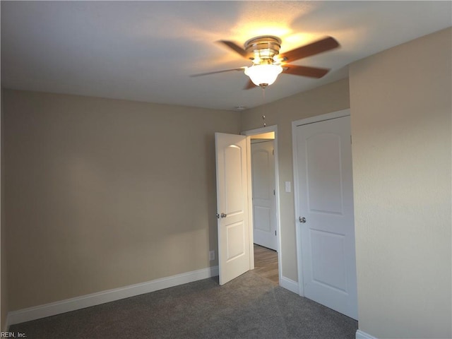 spare room featuring dark colored carpet and ceiling fan