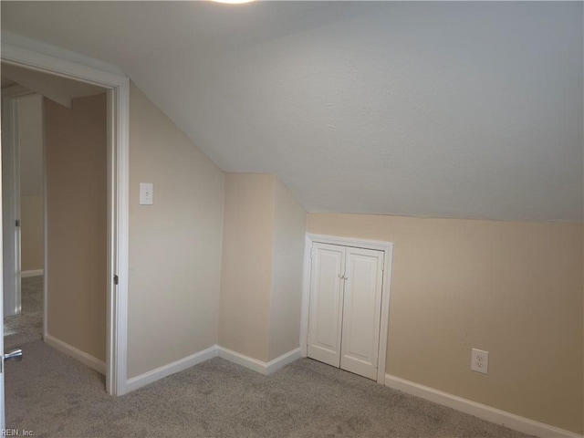 bonus room with light colored carpet and vaulted ceiling