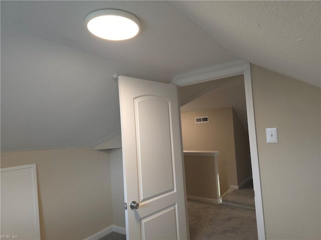 bonus room featuring lofted ceiling and dark colored carpet