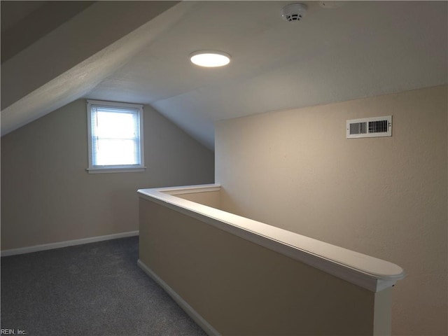 corridor featuring dark colored carpet and lofted ceiling