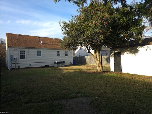 rear view of house with cooling unit and a lawn