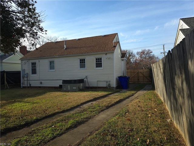 rear view of property with a lawn and cooling unit