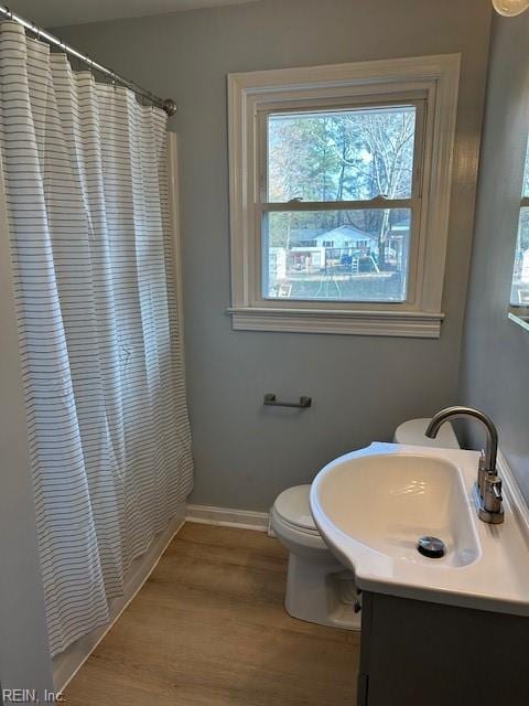 bathroom with hardwood / wood-style floors, vanity, toilet, and curtained shower