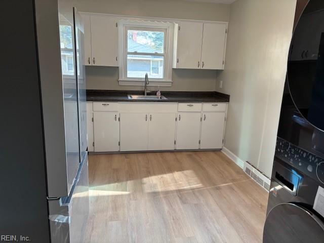 kitchen with light hardwood / wood-style flooring, white cabinetry, and sink