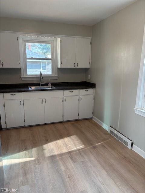 kitchen featuring white cabinets, light hardwood / wood-style floors, and sink