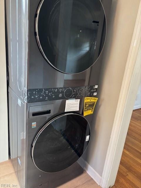 washroom with stacked washer and dryer and wood-type flooring