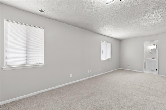 unfurnished room with light carpet and a textured ceiling