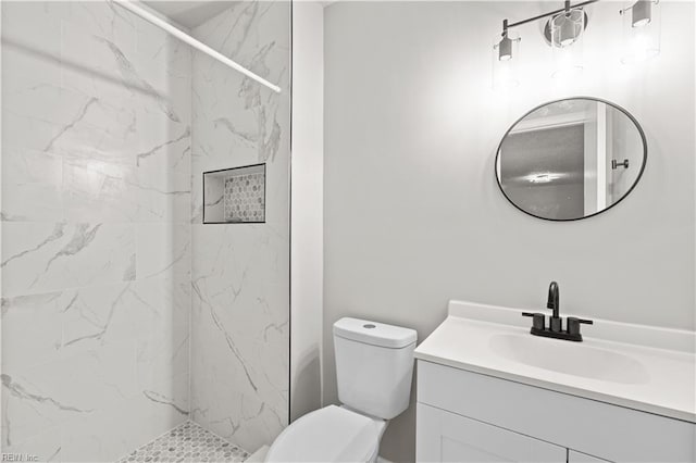 bathroom featuring tiled shower, vanity, and toilet