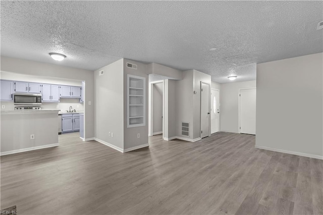 unfurnished living room featuring hardwood / wood-style floors, a textured ceiling, and sink