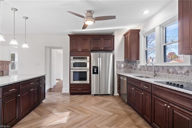 kitchen with appliances with stainless steel finishes, backsplash, sink, decorative light fixtures, and light parquet flooring