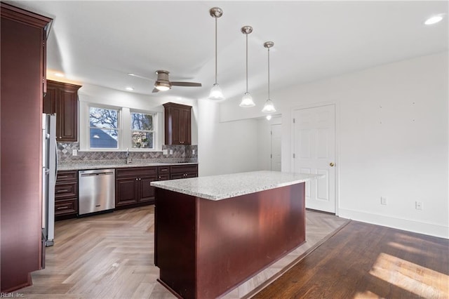 kitchen with stainless steel dishwasher, dark brown cabinets, ceiling fan, decorative light fixtures, and a kitchen island